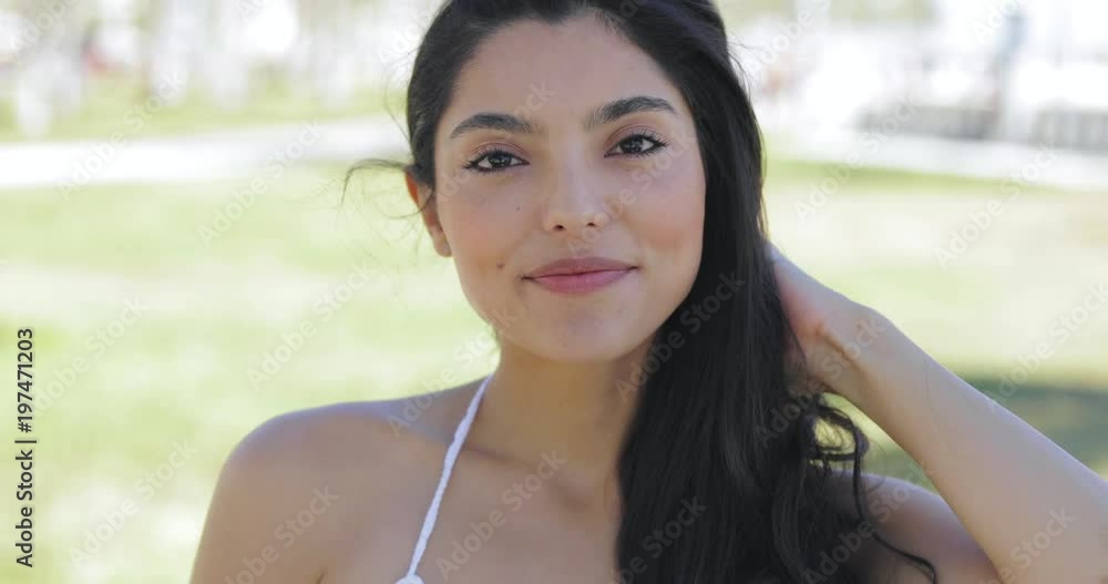 Confident pretty ethnic woman with long hair looking at camera with slight smile on tropical park background. Confident pretty ethnic woman with long hair looking at camera with slight smile on tropical park background.