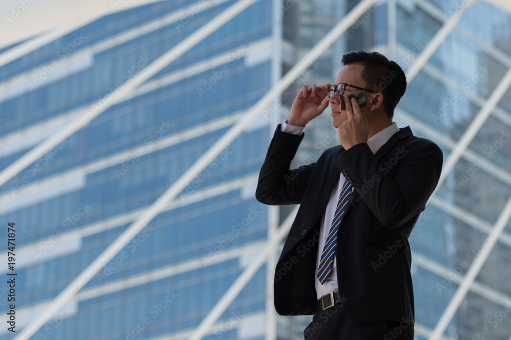 Young Asian businessman sweating due to hot climate. He wiping the face with wet wipes, perspiration, sweat in a city Bangkok Thailand. Young Asian businessman sweating due to hot climate. He wiping the face with wet wipes, perspiration, sweat in a city Bangkok Thailand.