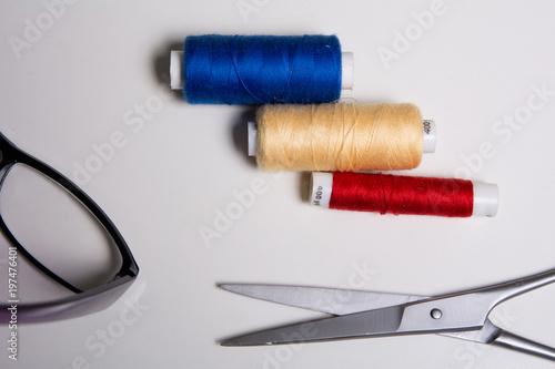 Three coils of multicolored threads, glasses and scissors photo