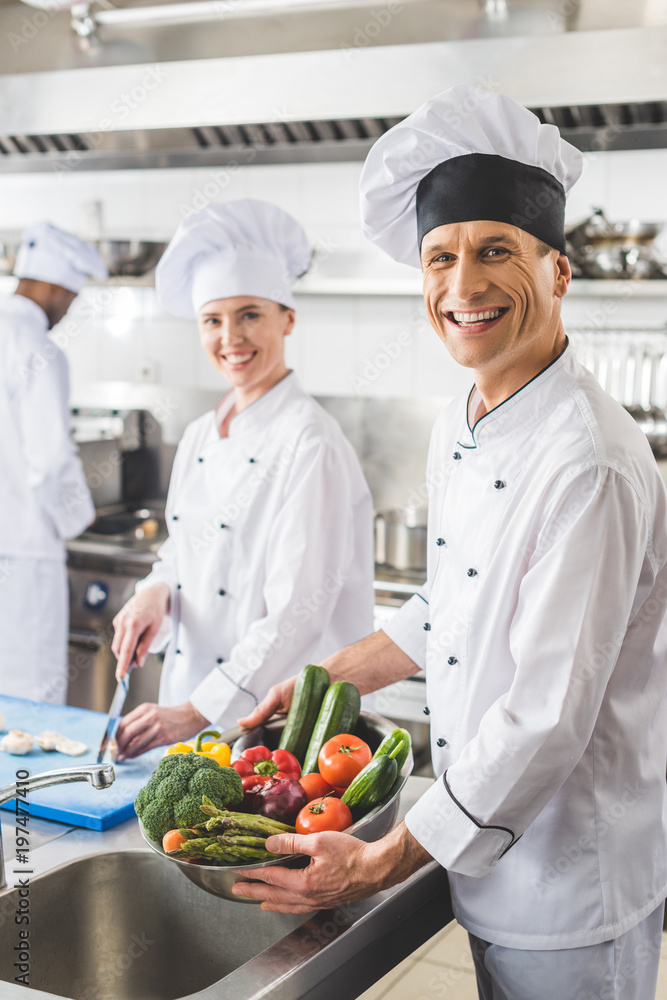 smiling chefs looking at camera at restaurant kitchen smiling chefs looking at camera at restaurant kitchen