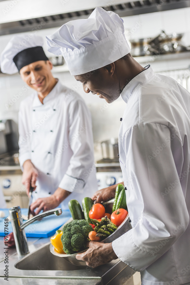 african american chef washing vegetables at restaurant kitchen