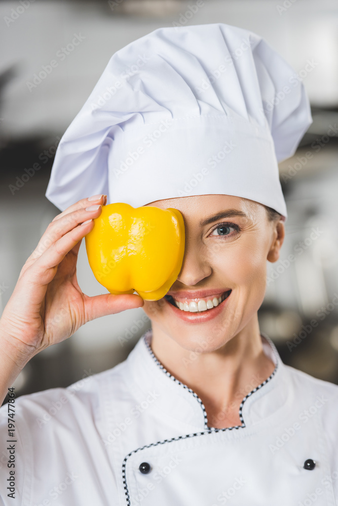 smiling chef covering eye with bell pepper at restaurant kitchen smiling chef covering eye with bell pepper at restaurant kitchen