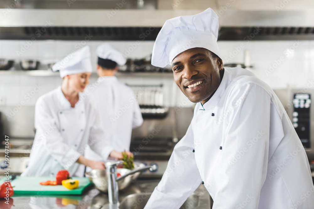 smiling african american chef looking at camera at restaurant kitchen