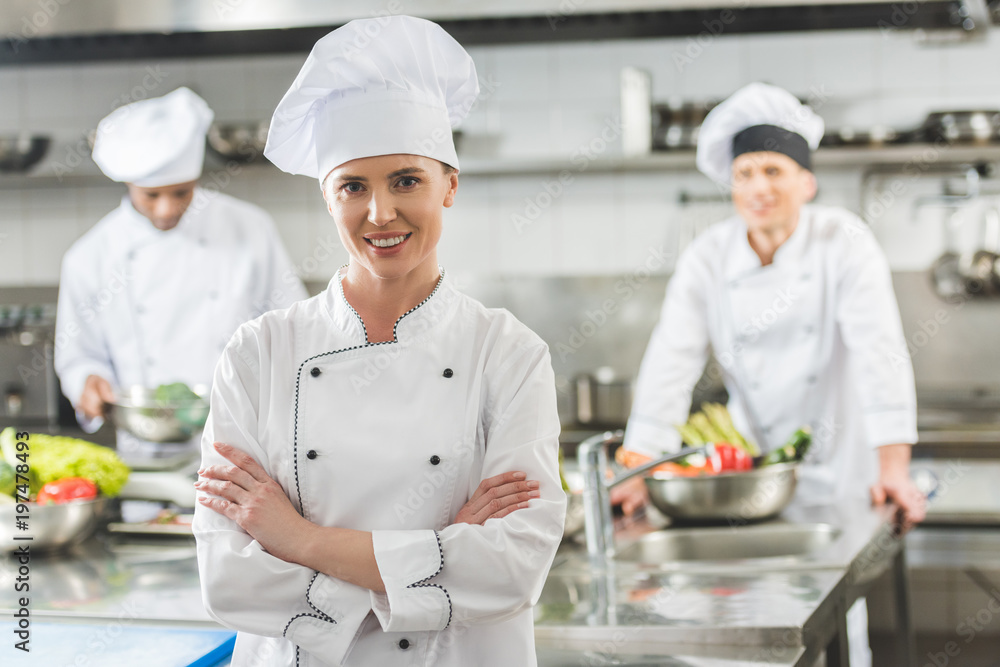 smiling chef standing with crossed arms and looking at camera at restaurant kitchen smiling chef standing with crossed arms and looking at camera at restaurant kitchen