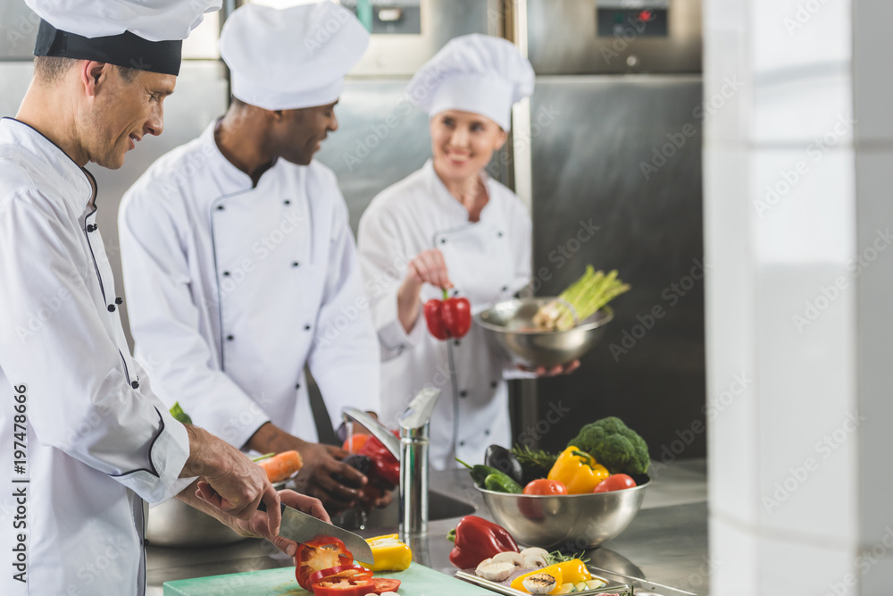 smiling multicultural chefs preparing food at restaurant kitchen smiling multicultural chefs preparing food at restaurant kitchen