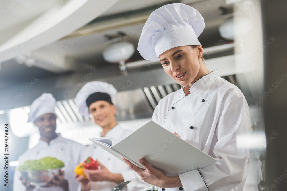 attractive chef reading recipe at restaurant kitchen