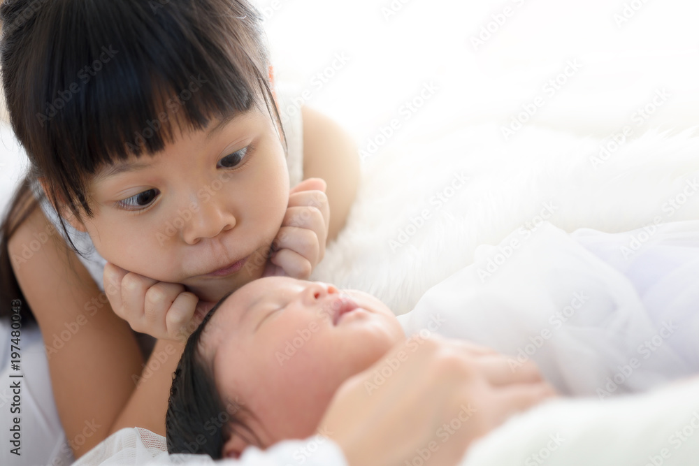 A girl look newborn baby lying on the bed. A girl look newborn baby lying on the bed.