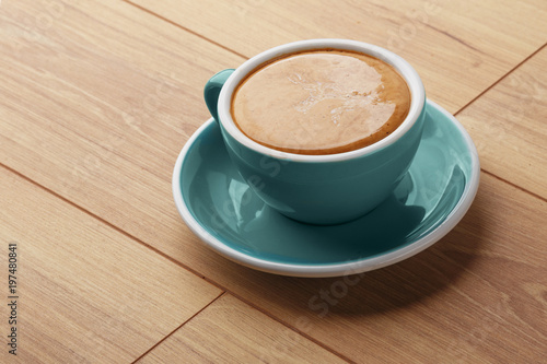 A cup of fragrant coffee in foam on a wooden table.
