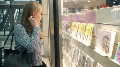 Young teenager girl looking at bookshop window at shopping mall

