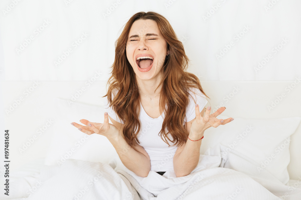 Portrait of an upset young woman sitting on bed Portrait of an upset young woman sitting on bed