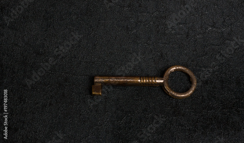 Old iron key isolated on dark surface © vuralyavas