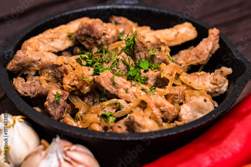 Fried pork in frying pan and vegetables