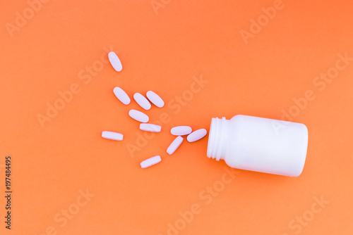 Pills are poured out of a jar on a orange background. Vitamins on a bright pink background. Top view. Flat Lay photo