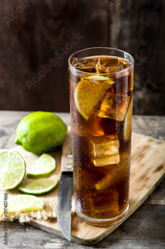 Cuba libre. Cocktail with rum, lime and ice on wooden table. 