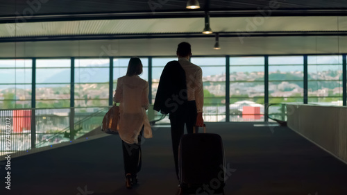 Couple in formal wear walking with bags in airport, business trip, partners