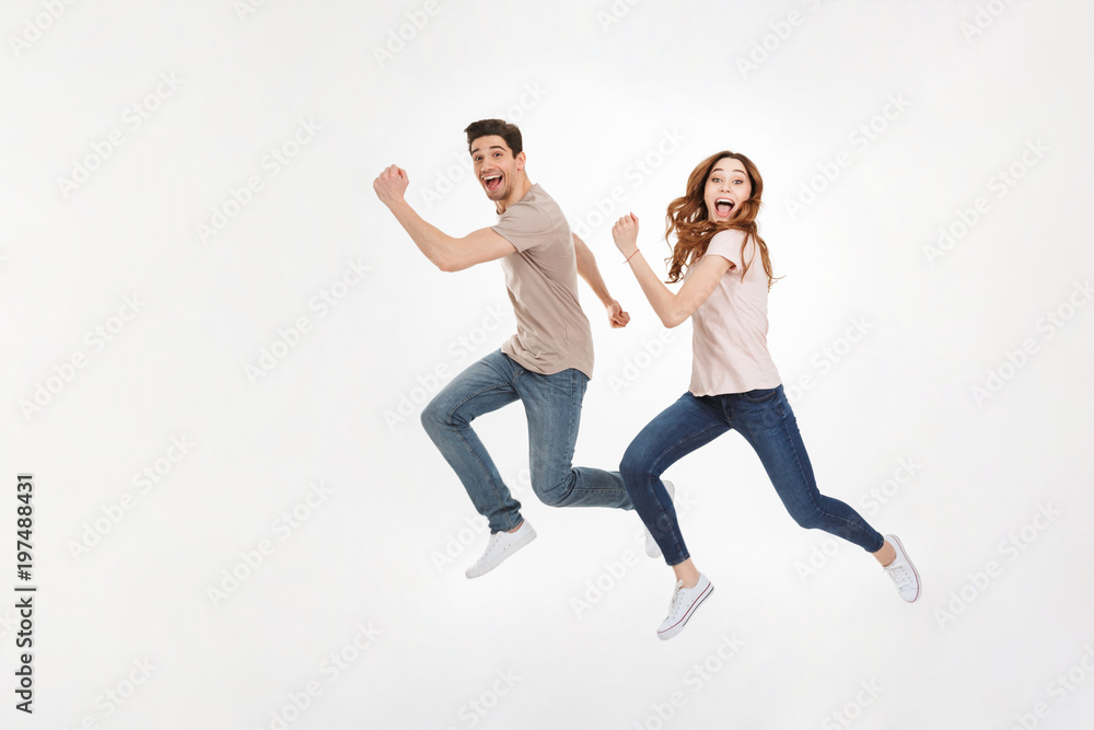 Full-length photo of happy couple man and woman in casual t-shirt running and smiling on camera with joyful look, isolated over white background