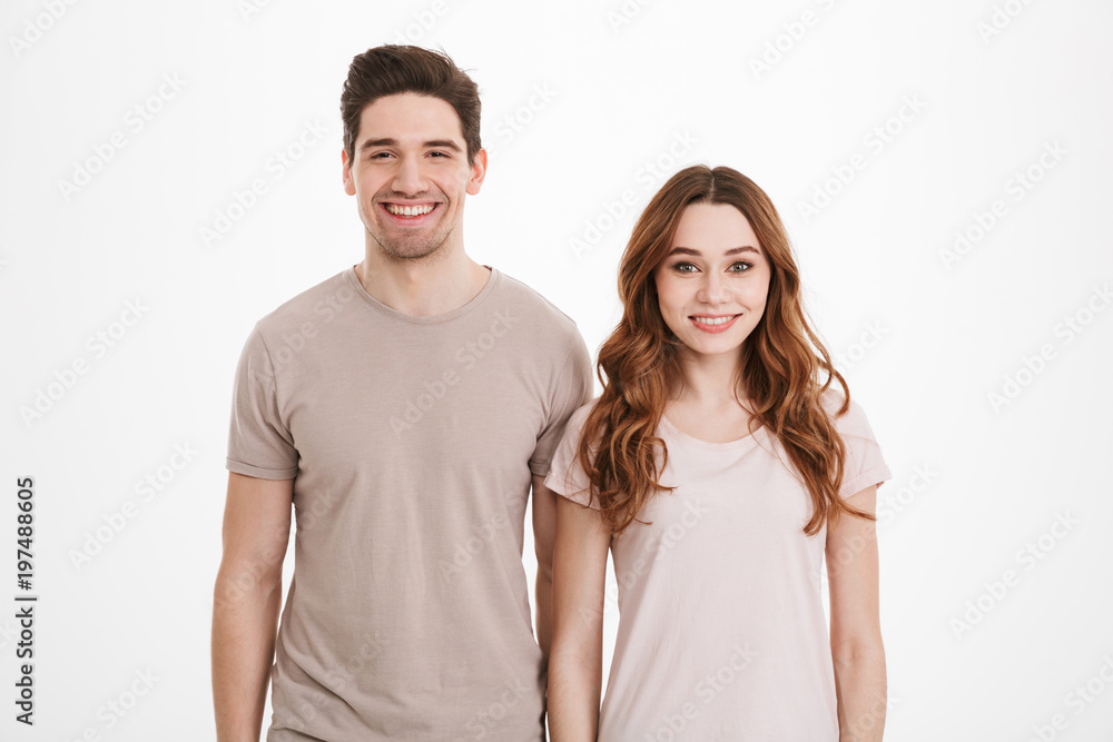 Young caucasian people 20s man and woman wearing beige t-shirts posing together on camera with happy smile over white background Young caucasian people 20s man and woman wearing beige t-shirts posing together on camera with happy smile over white background