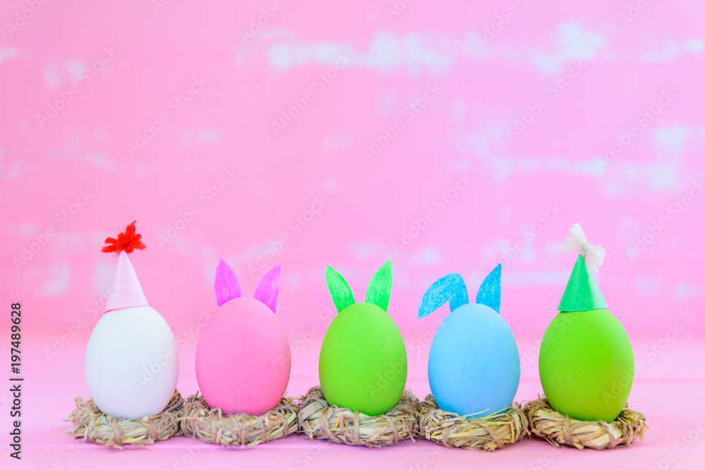 Soft focus of Row Easter eggs with colorful paper flowers on bright pink and white wooden background.
