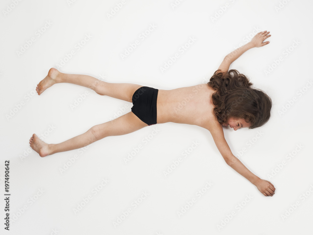 Adorable little boy in bathing suit lying on stomach with arms outstretched, isolated on light Adorable little boy in bathing suit lying on stomach with arms outstretched, isolated on light
