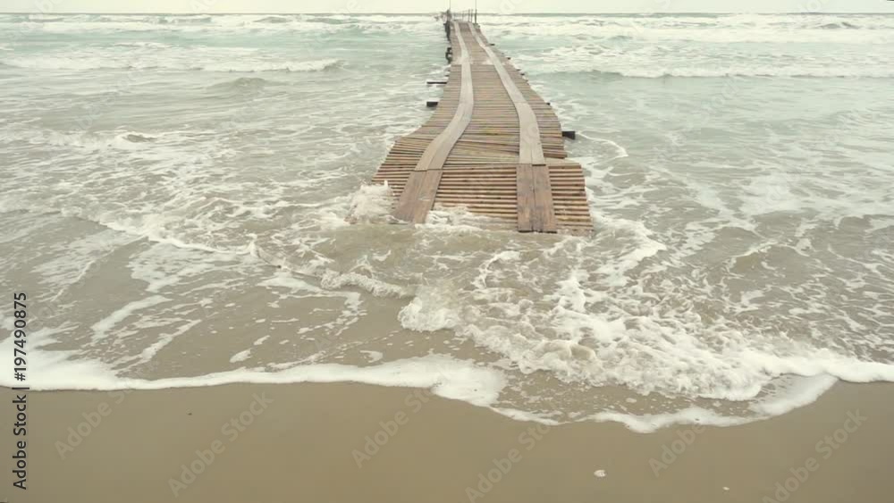 Slow motion wooden pier in the stormy ocean under the gray sky Slow motion wooden pier in the stormy ocean under the gray sky