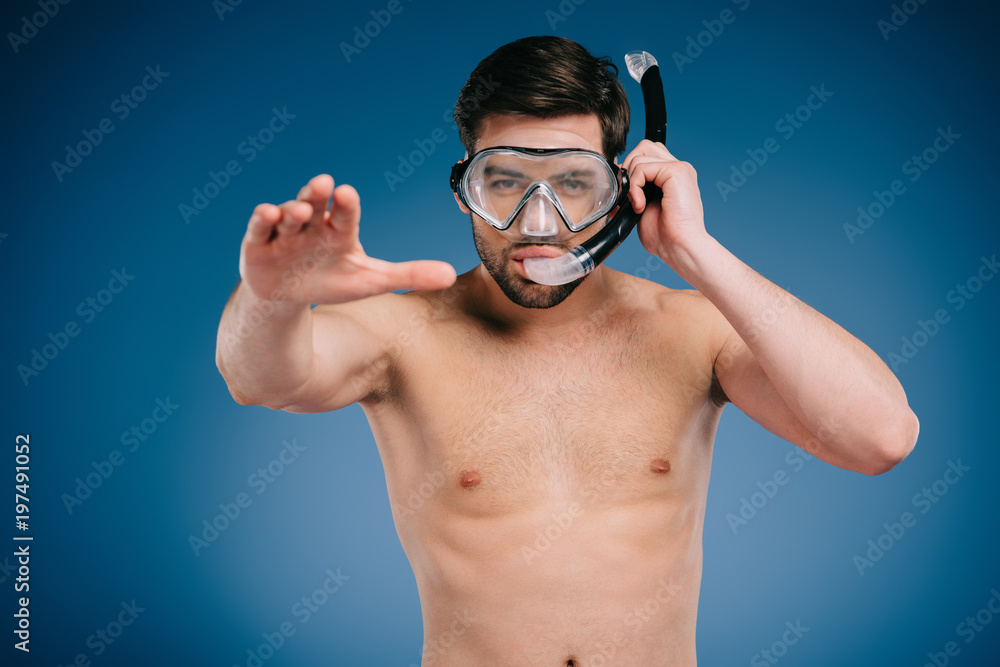 handsome shirtless young man in snorkel and diving mask looking at camera on blue handsome shirtless young man in snorkel and diving mask looking at camera on blue
