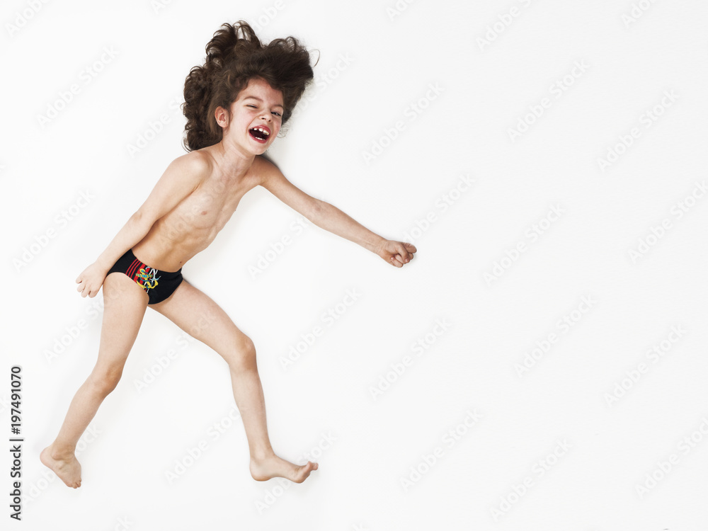Young Caucasian boy running action on light background