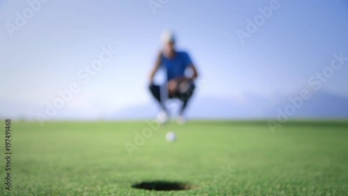 Golfer analyzing the trajectory and put. Pro golfer on a beautiful green, perfect light