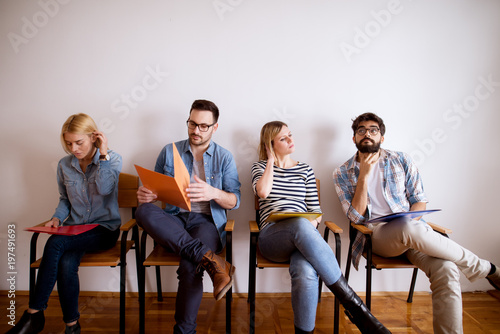 Canvastavla Group of upset and bored young people sitting in a row in the waiting room with a folder in hand before an interview with the entrepreneur