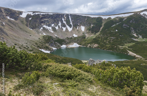 Mountain spring landscape with lake and the last snow on the hills.