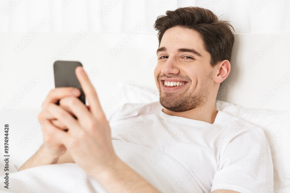 Close up happy young man holding mobile phone Close up happy young man holding mobile phone