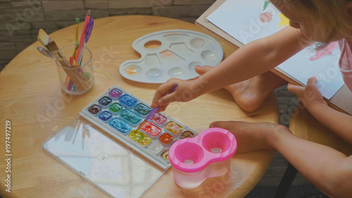 Child girl drawing by watercolor at home. photo