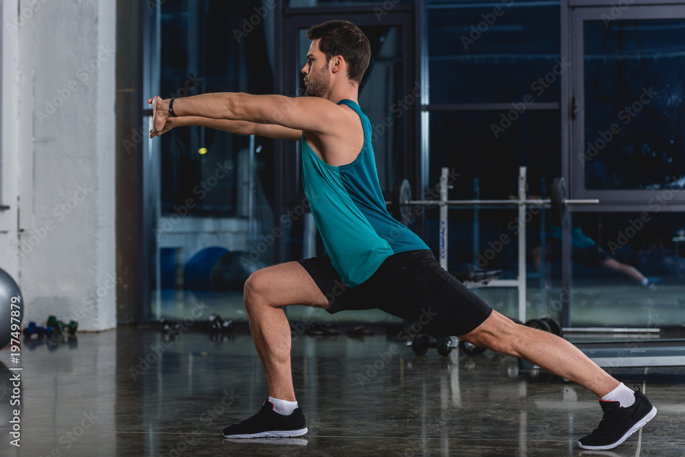 sportsman squatting and stretching legs in gym