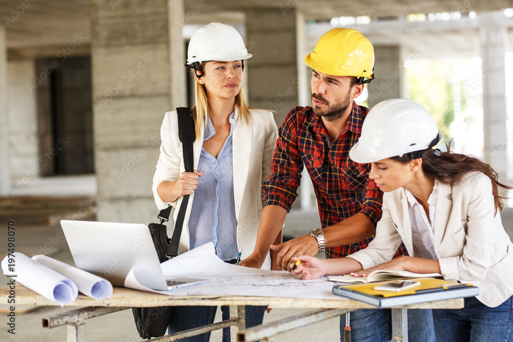 Two female inspectors and architects discuss with head engineer about construction project. Two female inspectors and architects discuss with head engineer about construction project.