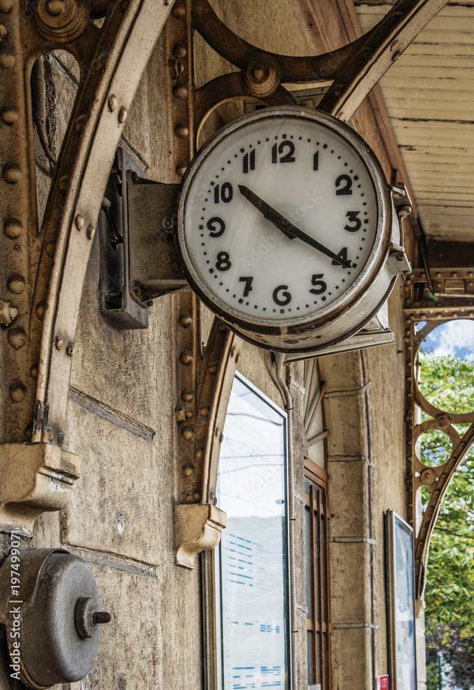 Old clock outside on wall  in train station, grunge effect