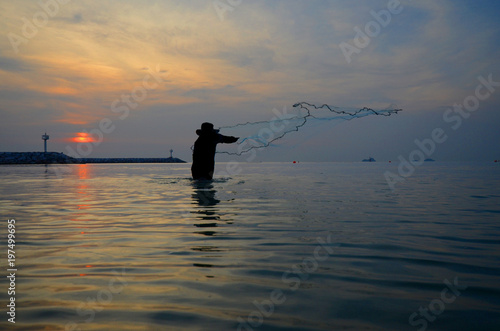 silhouette fisherman catch fish in the sea and sunset background