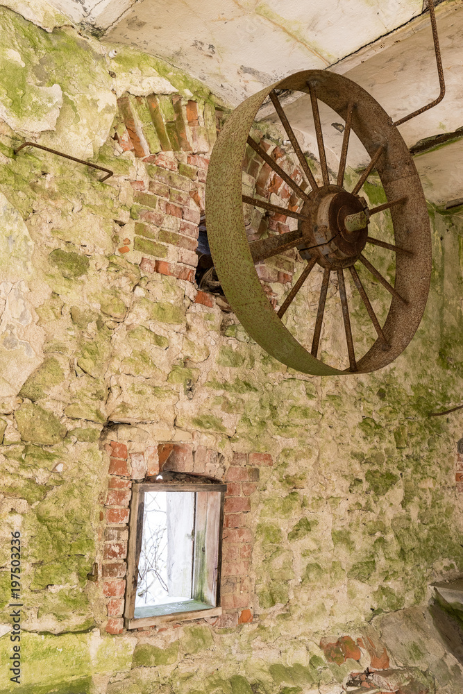 Abandoned watermill. Rusty wheels and green moss covered the old brick wall, natural background