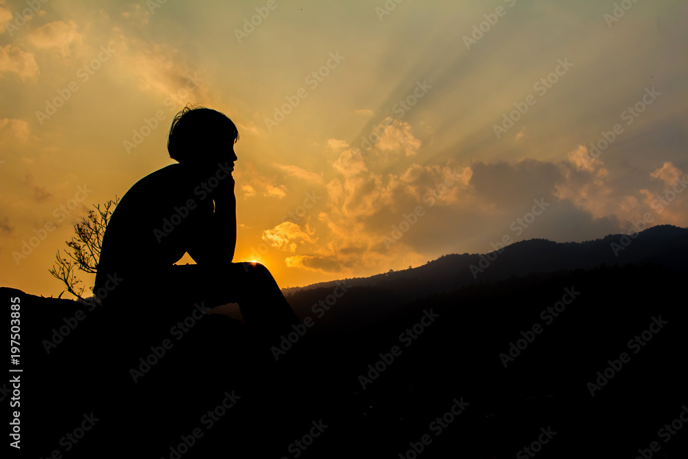 Silhouette little girl sitting on mountain at sunset time.