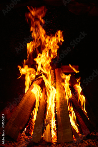 Burning firewood in the fireplace on a dark background.