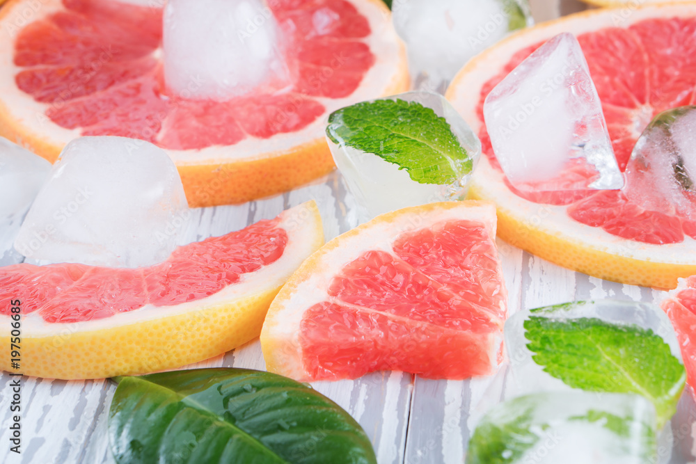 Red grapefruit slices, ice and mint on a white wooden background. The concept of a healthy diet. Detox. Red grapefruit slices, ice and mint on a white wooden background. The concept of a healthy diet. Detox.