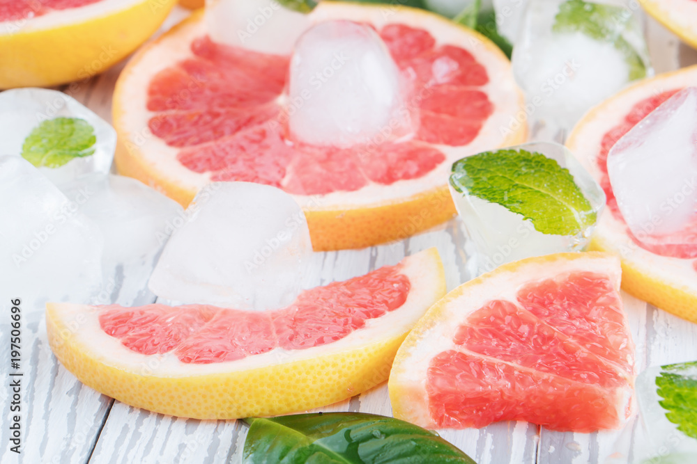 Red grapefruit slices, ice and mint on a white wooden background. The concept of a healthy diet. Detox. Red grapefruit slices, ice and mint on a white wooden background. The concept of a healthy diet. Detox.