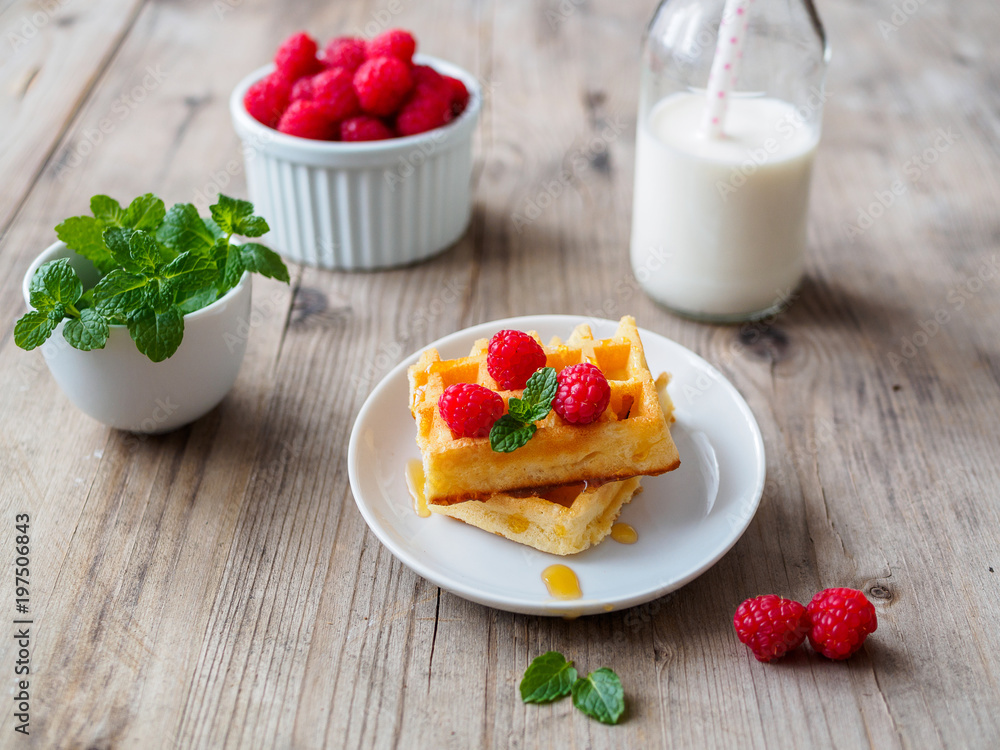 Selbstgebackene Waffeln mit frischen Himbeeren, Honig, Pfefferminze Selbstgebackene Waffeln mit frischen Himbeeren, Honig, Pfefferminze