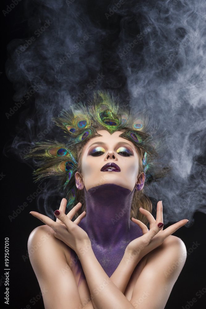 Beautiful Big Breast Girl Wearing Peacock Feathers In Her Hair And Artistic Violet Shiny Body Art On Her Neck Vanguard Makeup Artistically Crossed Her Hands In Theatrical Smoke Stock Photo Adobe