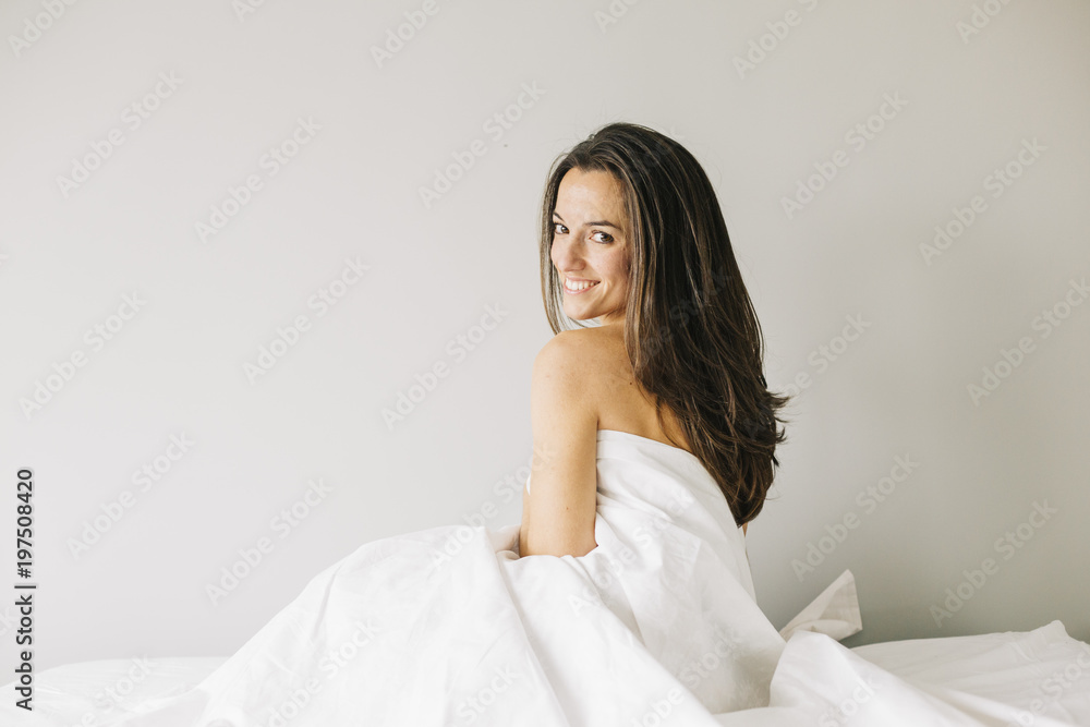 young beautiful woman sitting on bed, resting and smiling. Lifestyle at home. Indoors. Portrait young beautiful woman sitting on bed, resting and smiling. Lifestyle at home. Indoors. Portrait