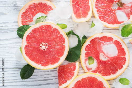 Top view of red grapefruit slices, ice and mint on a white wooden background. The concept of a healthy diet. Detox.