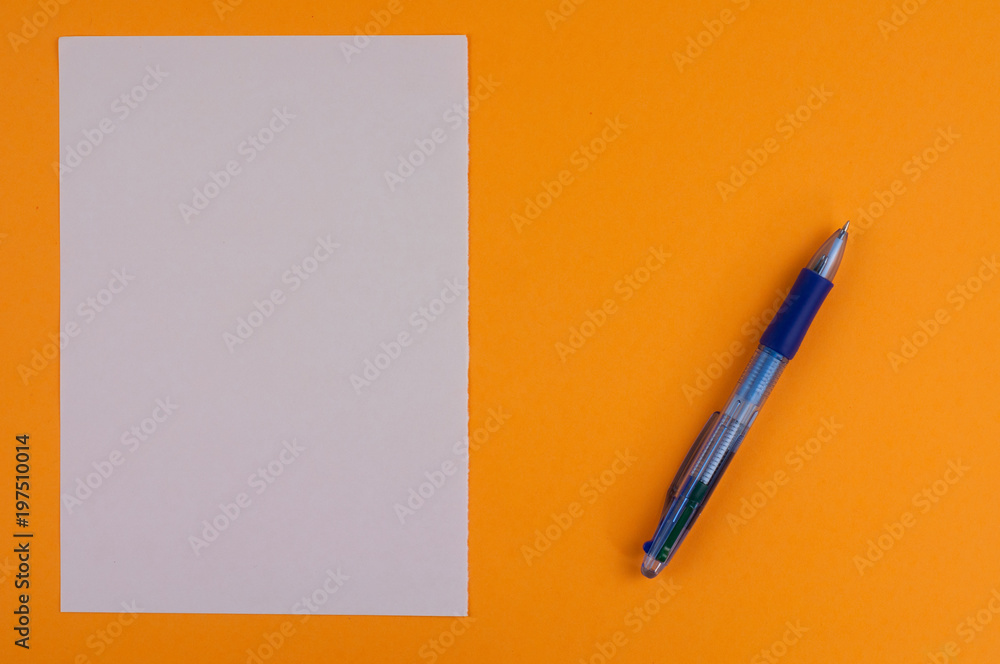 One multi color blue transparent ballpoint and white blank rectangle paper on background of orange paper with copy space One multi color blue transparent ballpoint and white blank rectangle paper on background of orange paper with copy space