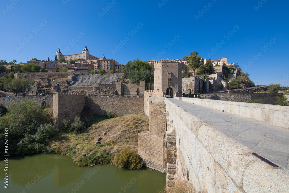 cityscape of Toledo city with Alcazar from Alcantara bridge, landmark and monument from ancient Roman age, and green water of river Tagus, Tajo in Spanish, Spain, Europe
