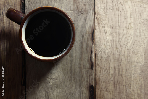 Black coffee in cup on wooden table.