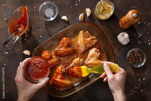 Hands brush baked wings with the bbq souce.