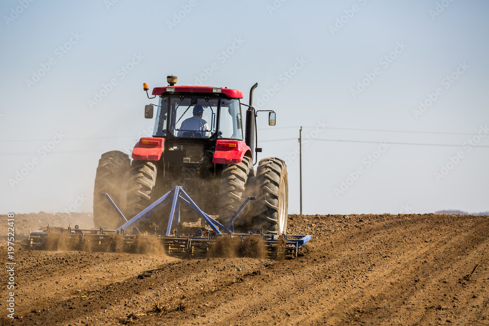Obraz premium Tractor cultivating field at spring