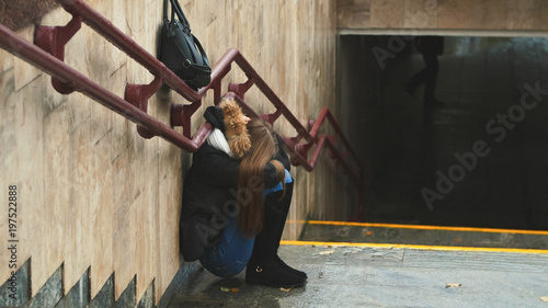 Obraz na plátně Young girl on the stairs in the subway depressed sitting alone obscures the face with his handsand crying